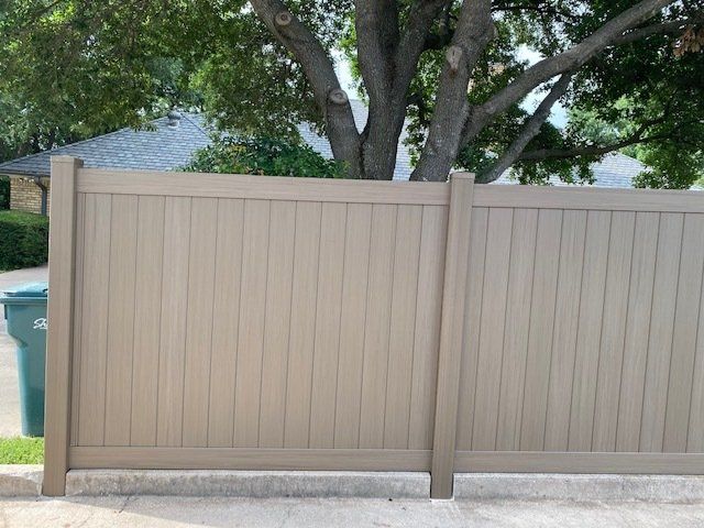A tan wooden fence with a tree in the background