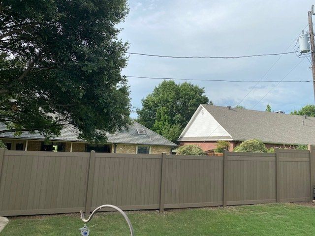 A brown fence is in the backyard of a house.