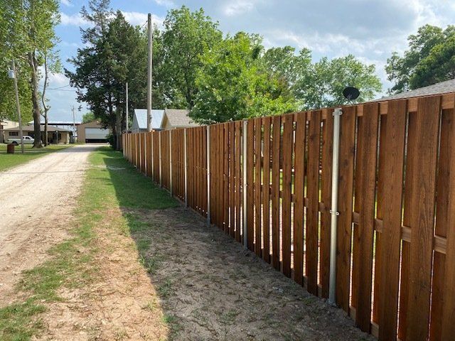 A wooden fence is along the side of a dirt road.