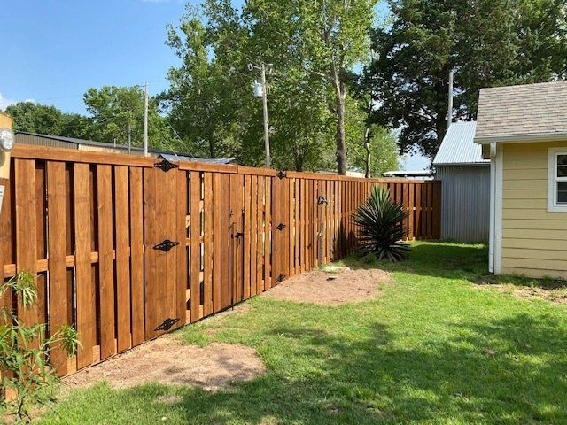 A wooden fence is in the backyard of a house.