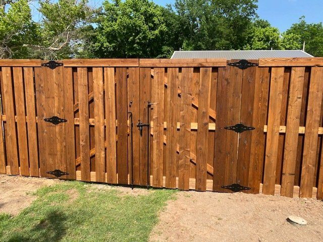 A wooden fence with a gate is sitting on top of a dirt field.