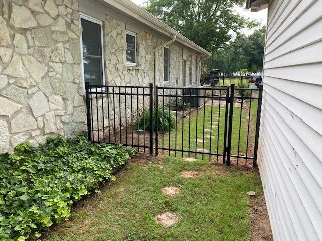 A stone house with a black fence surrounding it