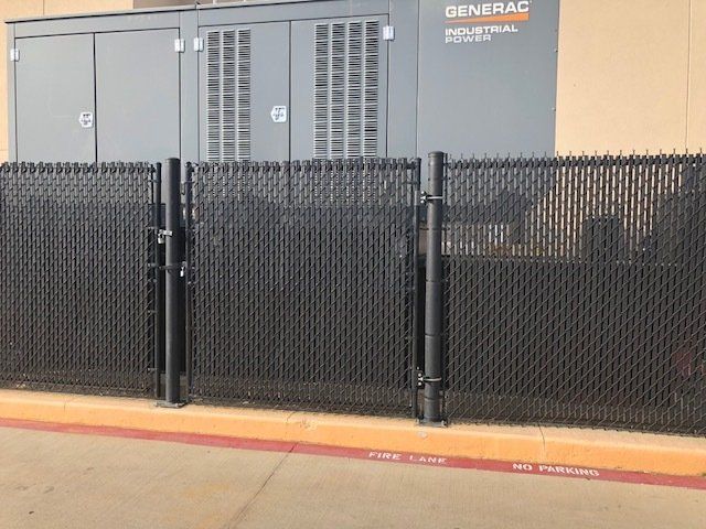 A black chain link fence with a generator in the background