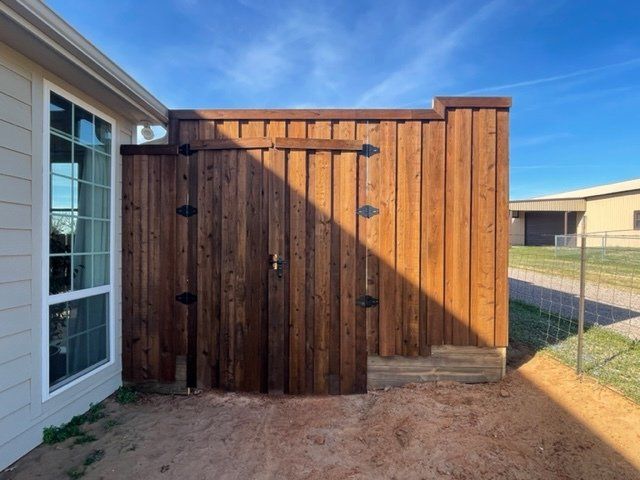 A wooden fence is next to a house with a window