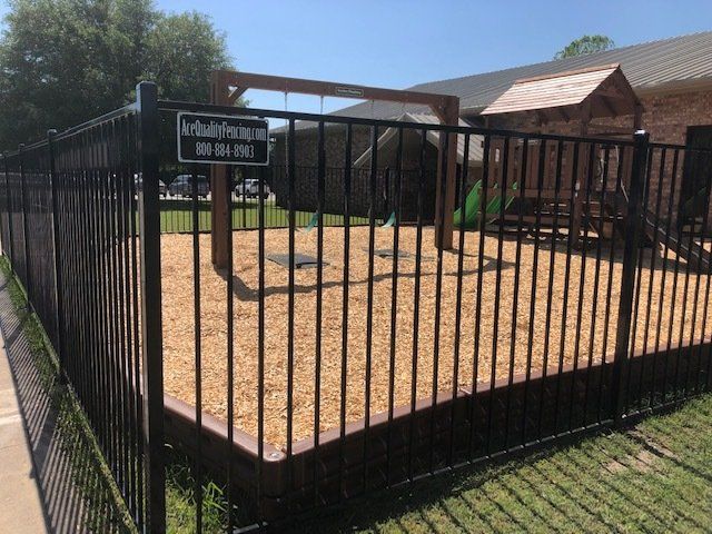 A black fence surrounds a playground with a sign that says adults only