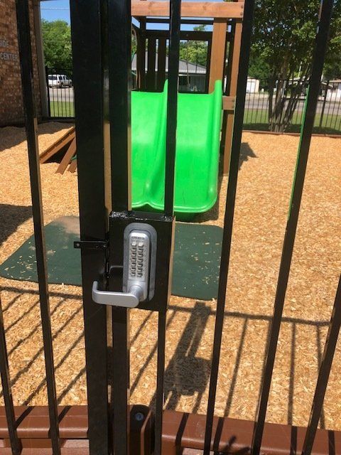 A green slide is behind a fence with a combination lock