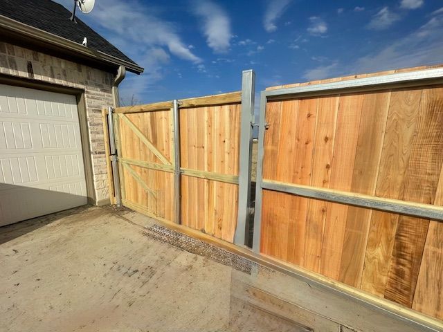 A wooden fence is sitting in front of a garage.