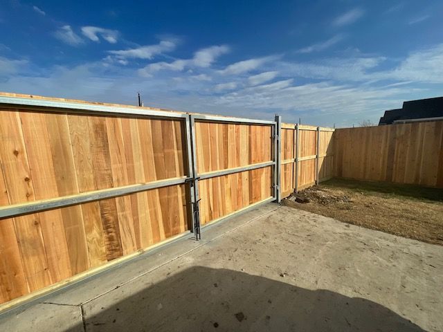 A wooden fence with a metal frame is in a backyard.