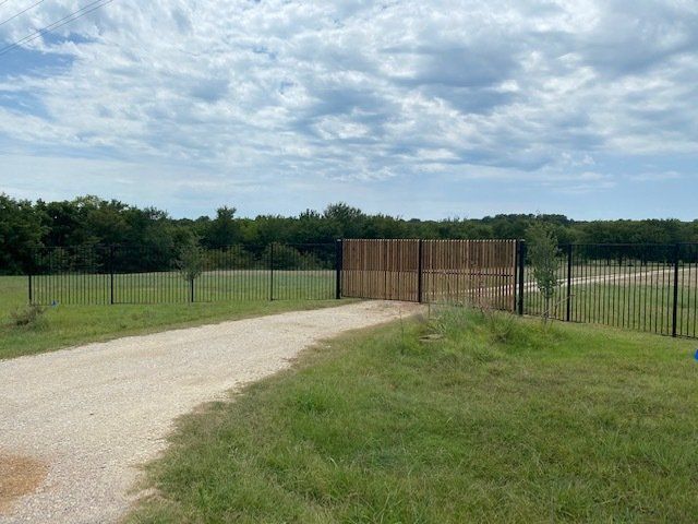 A dirt road leading to a wooden gate in a field