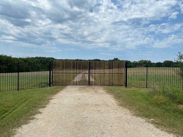 A dirt road leading to a fenced in field.