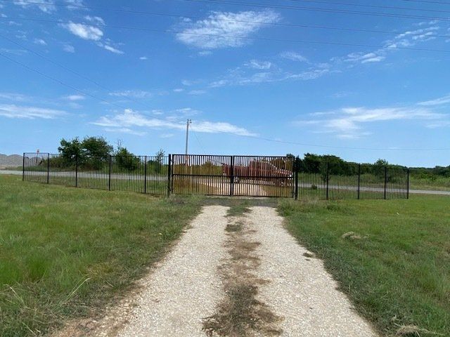 A dirt road leading to a gate in a field.
