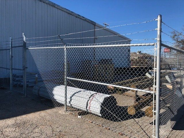 A chain link fence is surrounding a large white pipe.