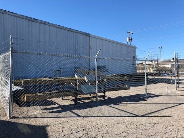 A chain link fence surrounds a large white building.