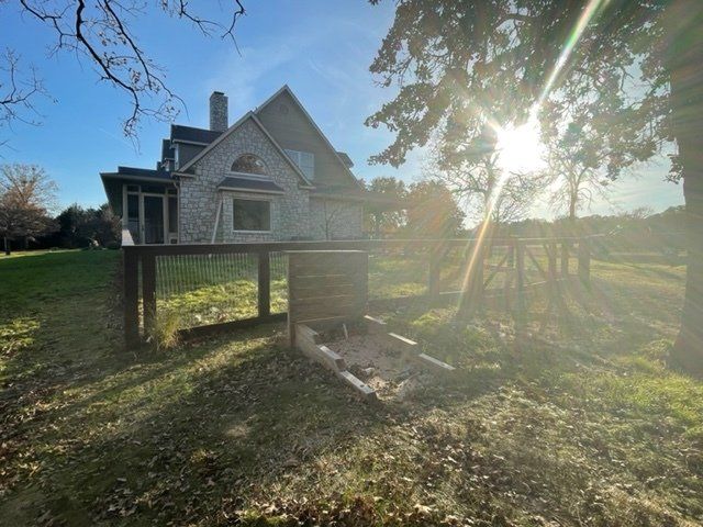 The sun is shining through the trees in front of a house