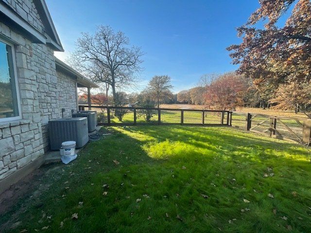 The backyard of a house with a fence and a lot of grass.
