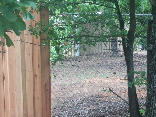 A wooden fence with a chain link fence behind it