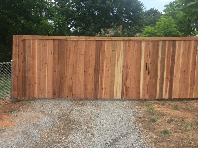 A wooden fence is sitting on top of a gravel road.