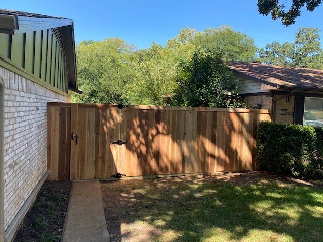 A wooden fence with a gate in the backyard of a house.