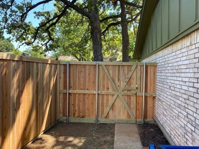 A wooden fence with a gate in the backyard of a house