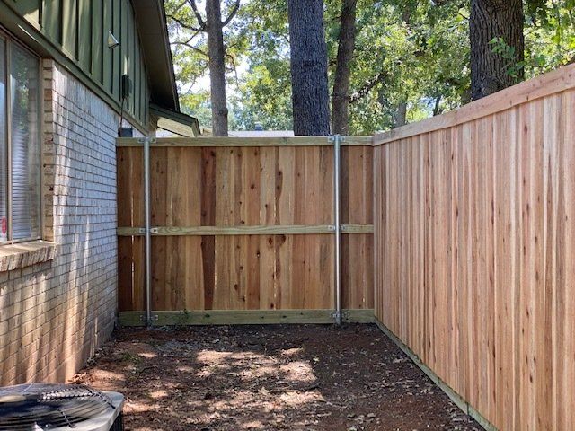A wooden fence is in the backyard of a house.