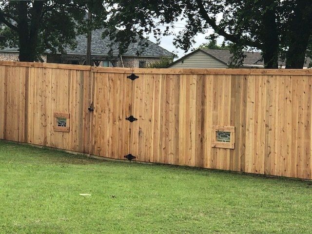 A wooden fence with a gate in the middle of a lush green field.