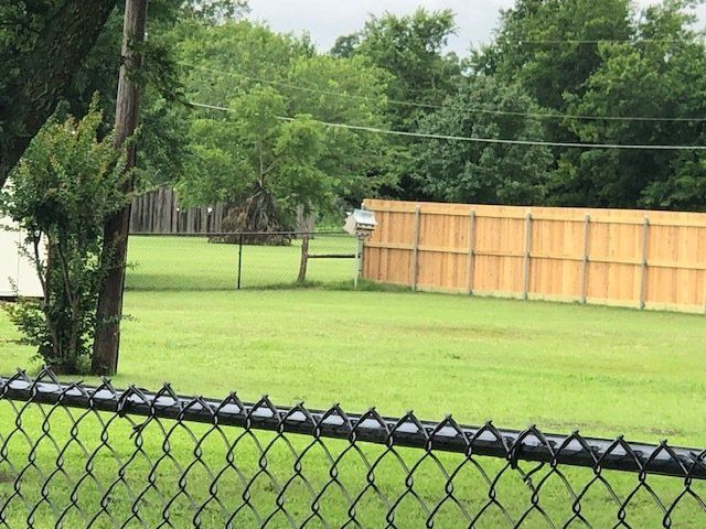 A chain link fence with a wooden fence behind it