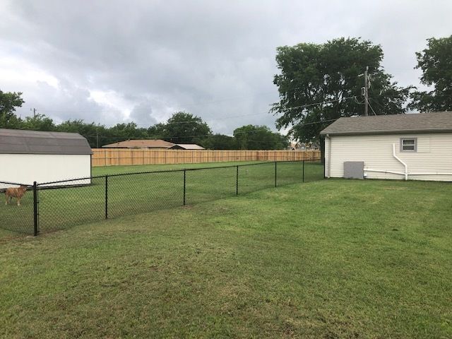 A fenced in yard with a house in the background.