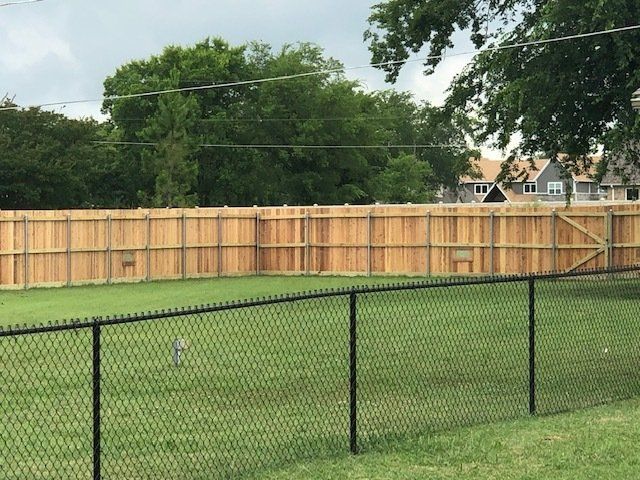 A wooden fence surrounds a lush green field.