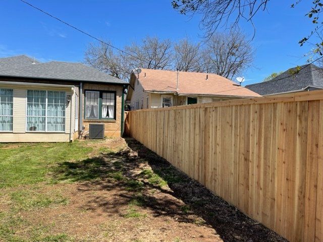 A wooden fence is in the backyard of a house.