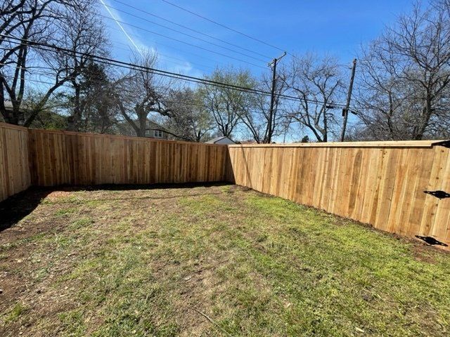 A wooden fence surrounds a lush green yard.