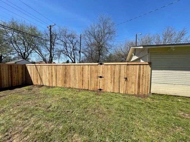 A wooden fence with a gate in the backyard of a house.
