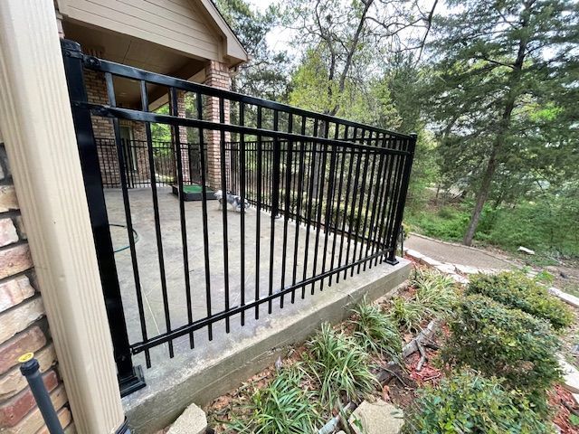 A black metal fence is sitting next to a brick building.