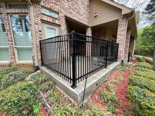 A black fence is in front of a brick house.