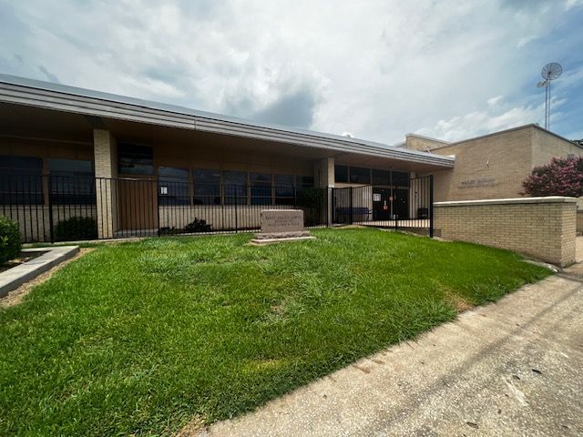 A large building with a lush green lawn in front of it.