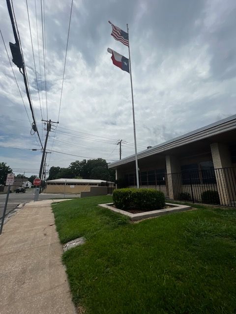 Three flags are flying in front of a building
