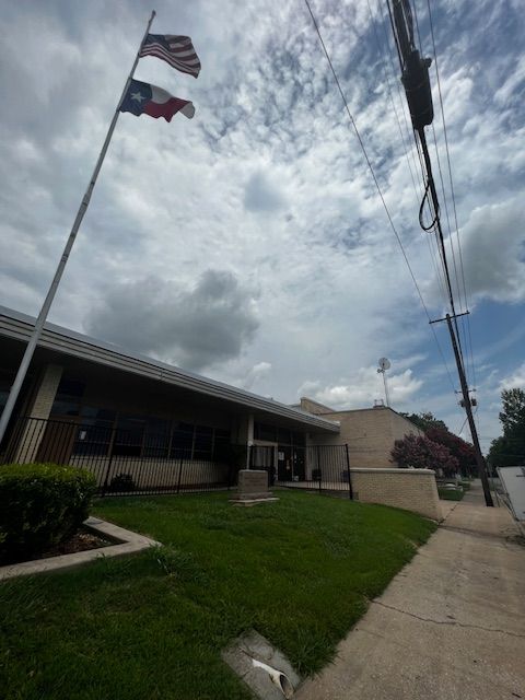 Two flags are flying in front of a building