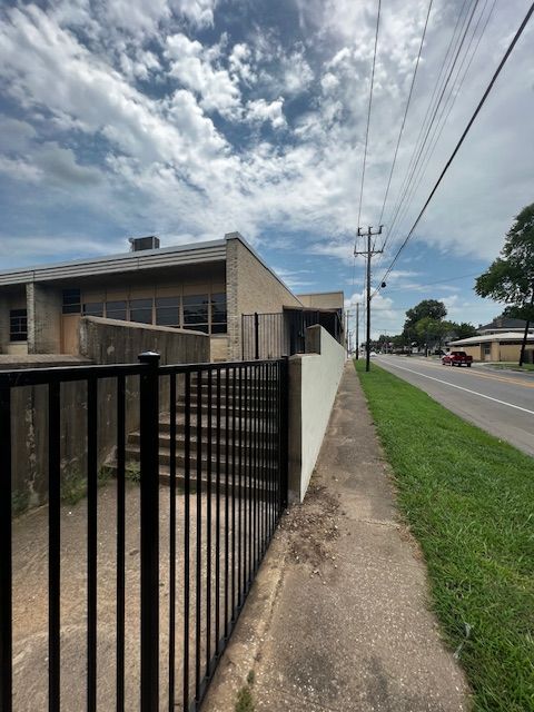 A fence along a sidewalk with a building in the background