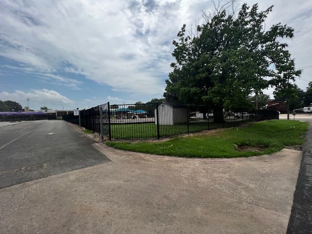 A fence surrounds a grassy area with a few trees in the background