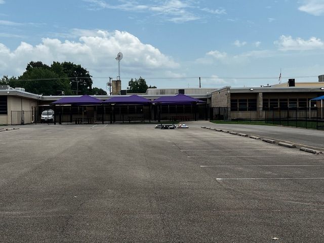 An empty parking lot in front of a building with a purple awning