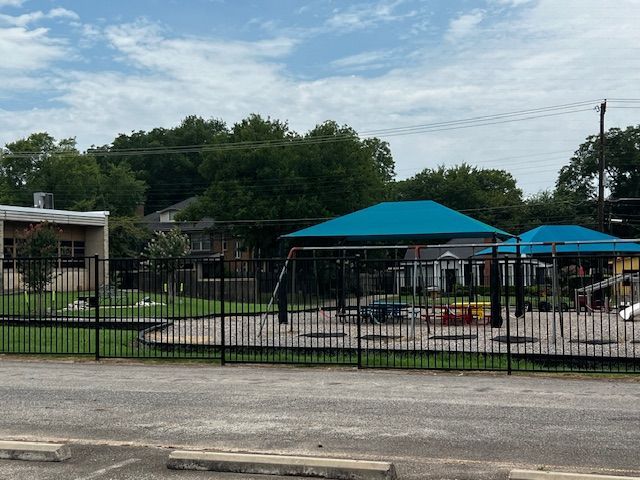 A playground with a blue canopy and a fence around it