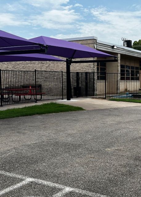 A parking lot with purple umbrellas in front of a building