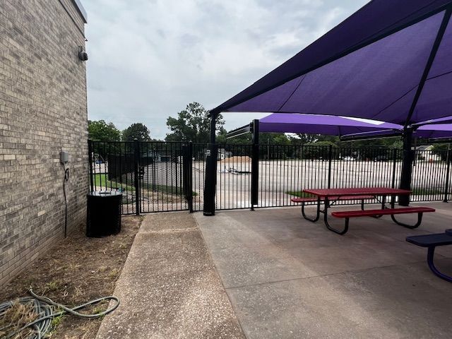 A picnic area with a purple umbrella and a red table