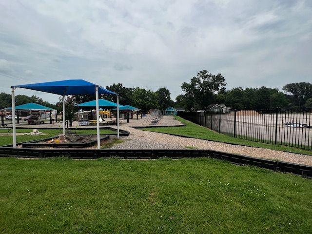 A park with a blue umbrella and a sandbox.