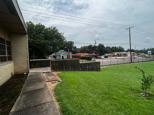 A sidewalk leading to a building with a fence in the background.