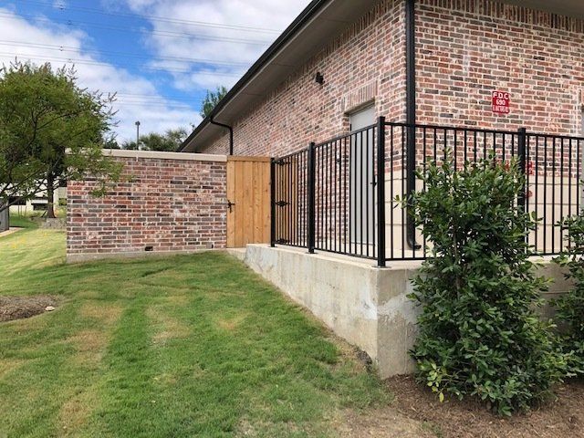 A brick building with a black railing and a wooden gate.