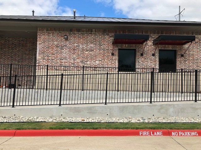 A brick building with a fence around it and a sign that says no parking.