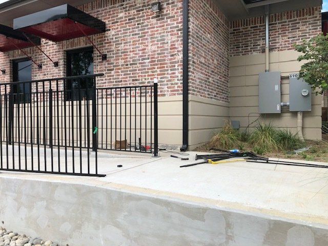 A metal fence is being built in front of a brick building.