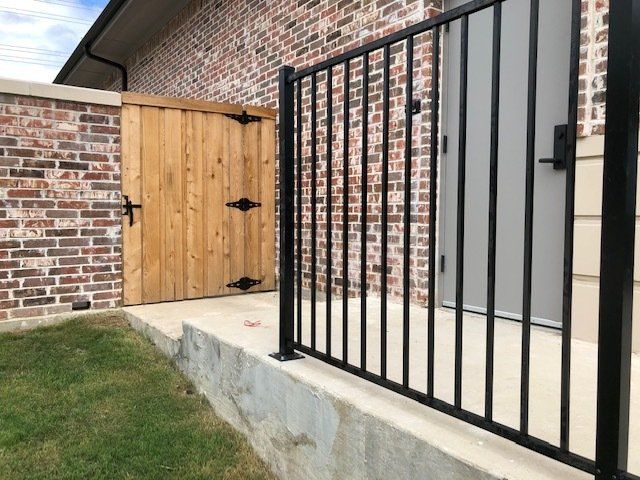 A brick house with a wooden gate and a black fence.