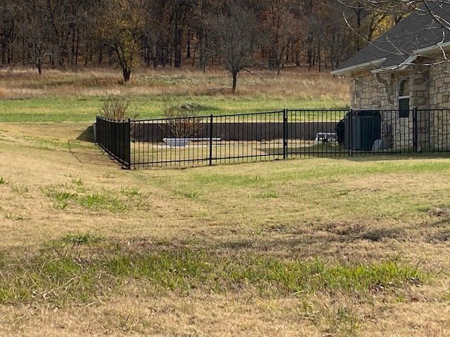 There is a fence in the middle of a field next to a house.