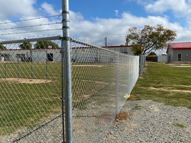 A chain link fence is surrounding a grassy field.